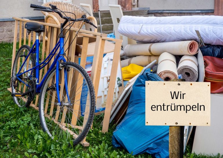 Über META-Entrümpelung Ein blauer Fahrrad steht neben verschiedenen Möbeln und einer Beschilderung „Wir entrümpeln“.